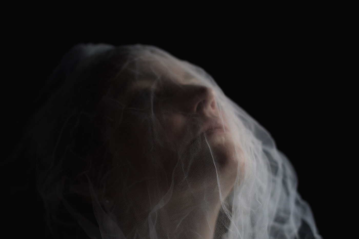 Moody editorial bridal veil portrait against a dark background
