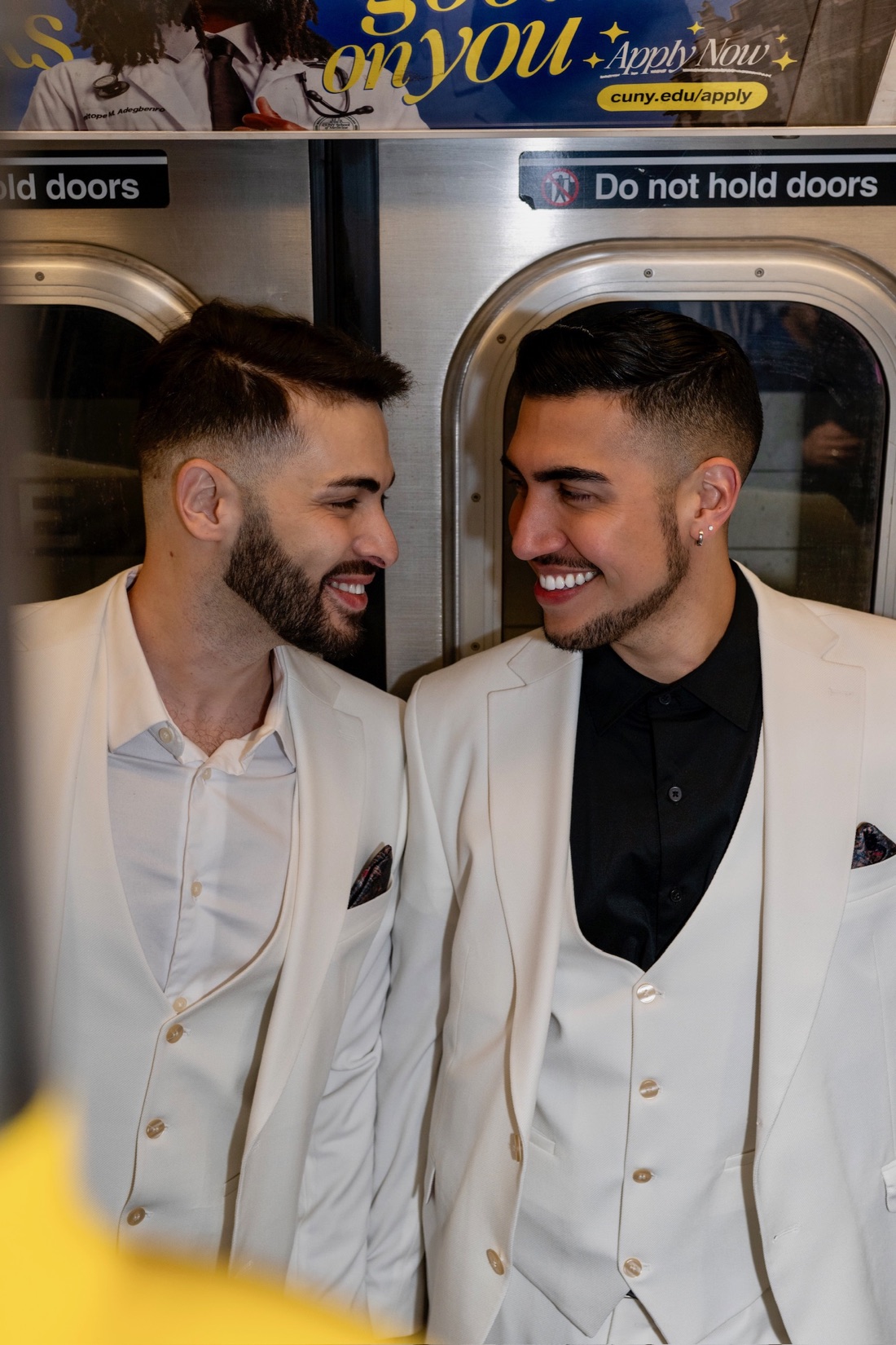 Two grooms smiling together on a New York subway